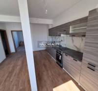 The kitchen of a 2-room apartment with wooden floors and gray cabinets.
