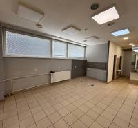 An empty commercial space with windows, a radiator, and a sink on a tiled floor.