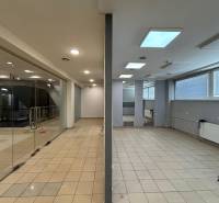 Empty commercial spaces with tiled floors and a glass entrance area.