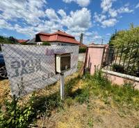 Plots - housing on Mlynská Street in Biel, with a fence and a building in the background.