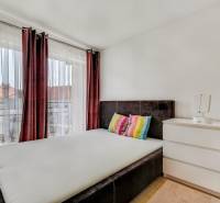 A bedroom in a family house with a bed and a dresser, complemented by colorful pillows.