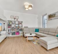 Living room in a family house with a sofa, bookshelf, and table on a wooden floor.
