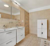 A bathroom in a family house with a double sink, white cabinet, and bathtub.