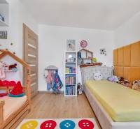 Children's room in a family house with beds, shelves, and toys, light wooden floors.