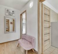 A hallway in a family house with a pink bench, a mirror, and wooden doors.