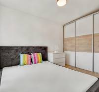 A bedroom in a family house with colorful pillows and a built-in wardrobe.