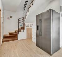 A refrigerator in the hallway of a family house with a wooden staircase and decorations on the walls.