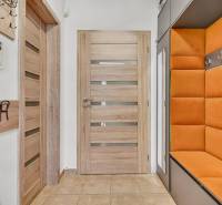 The entrance hall in the family house with an orange bench, wooden doors, and wall hooks.