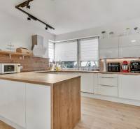 A kitchen in a family house with white cabinets, a wooden countertop, and kitchen appliances.