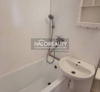 Bathroom in a studio apartment with a bathtub, mirror, and sink.