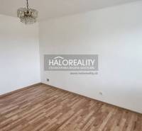 An empty room in a one-room apartment with a parquet floor and a ceiling light.