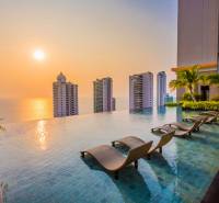 Pool, loungers, and the panorama of apartment construction in Pattaya at sunset.