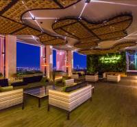 Luxury apartment space with a view of the city's evening lights, a green wall, and comfortable seating.