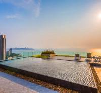 Apartment construction in Pattaya with a rooftop pool and sea view at sunset.