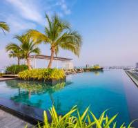 Infinity pool and palm trees on the rooftop with a view of the city skyline in Pattaya, apartment construction.
