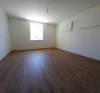 A room with a wooden floor and a bright window in a family house.