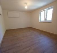 Empty room with laminate flooring and white walls in a family house.