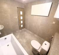 Bathroom in a family house with a bathtub, sink, and toilet, light tiles.