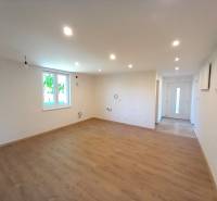 A spacious living room in a family house with wooden flooring and white walls.