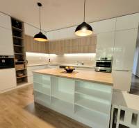 A kitchen in a 3-room apartment with an island, wooden details, and built-in appliances.