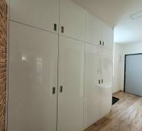 Entrance hallway in a 3-room apartment with white cabinets and brick cladding.
