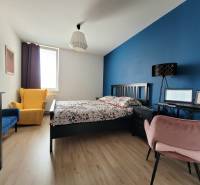 A bedroom in a 3-room apartment with colorful chairs and a work corner.