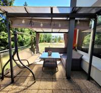 Terrace of a 3-room apartment in Banská Bystrica with a swing and a table for sitting.