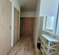 A bright hallway with wooden doors and brick decor in a 3-room apartment.