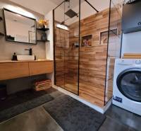 Bathroom in a 3-room apartment with a wooden shower and a washing machine.
