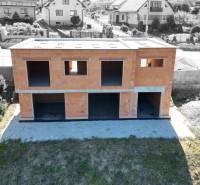 An unfinished family house in Trnová Žilina, surrounded by other houses and greenery.