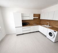 A kitchen in a one-room apartment with white furniture and wooden decor.