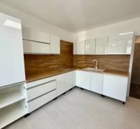 A kitchen with white cabinets and wooden paneling in a studio apartment.
