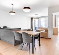 Dining room and living room in a 2-room apartment with wooden flooring and modern lighting.