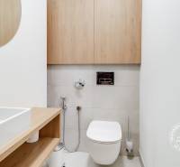 White bathroom with a wooden cabinet and sink in a 2-room apartment.