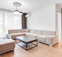 Living room in a two-room apartment with a white sofa and wooden floor.
