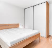 Bedroom in a 2-room apartment with a wooden bed, nightstands, and a built-in wardrobe.