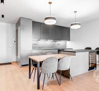 A kitchen with a dining table, gray cabinets, and ceiling lights in a 2-room apartment.
