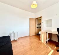 A room with a wooden floor, a black chair, a table, and baskets in a 3-room apartment.