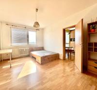 A room in a 3-room apartment with light furniture, a bed, and a large window.