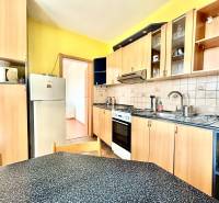 A kitchen in a 3-room apartment with wooden cabinets, a stove, and a refrigerator.
