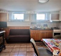 Interior of a cottage with a kitchen, stove, sofa, and decorated table, suitable for relaxation and cooking.