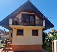 The exterior of the cottage in Senec with an illuminated balcony and fencing.