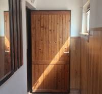 Entrance hallway in a cabin with wooden paneling and tiles, bright and cozy environment.