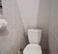 A toilet in a cabin with slanted walls and light tiles.