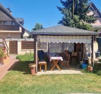 The garden of the cottage in Senec with a gazebo, bench, and flower pots full of plants.