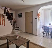 Interior of a cabin with a staircase, a table, and a flower on the table, decorated with wooden elements.