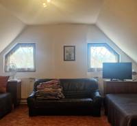 Attic room of the cottage with a sofa, two beds, and a television.