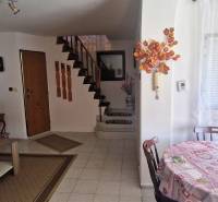 The interior of a cabin with a wooden staircase, dining table, and couch in a cozy atmosphere.