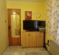 A room in a cottage with a TV and floral curtains, a peaceful atmosphere.