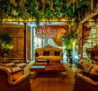 Luxurious living room with a chandelier, plants, and golden curtains as part of apartment construction.